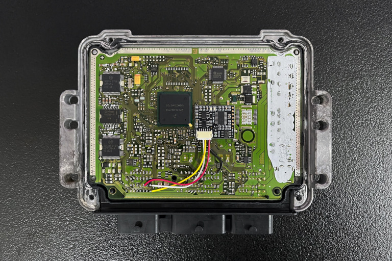 A view of the emulator neatly installed inside the open engine control unit casing. This setup offers a clean, protected solution that ensures permanent immobilizer signal emulation directly at the source, shielding the device from external elements.
